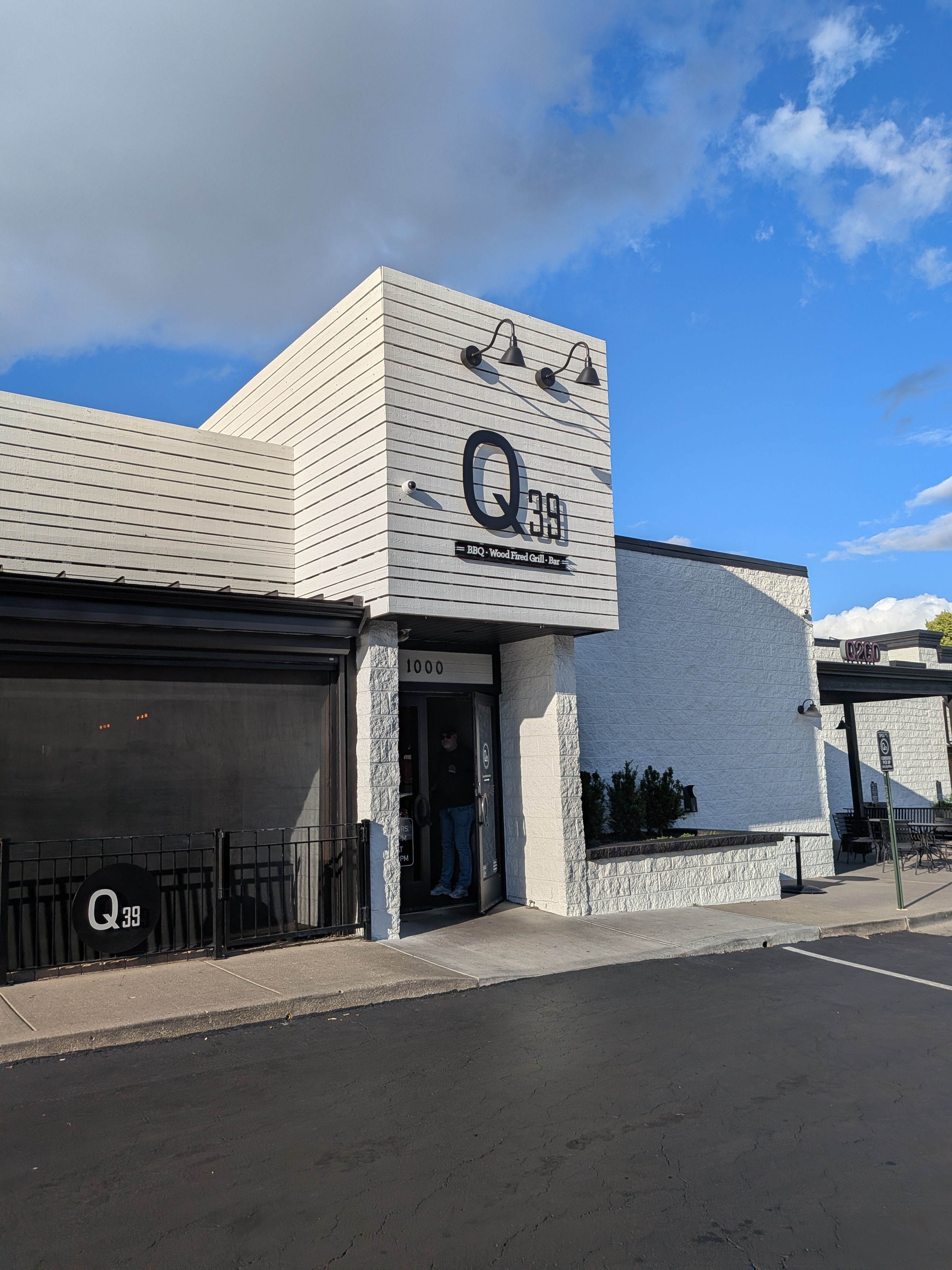 The front entrance of Q39, a white building with the Q39 sign and the words BBQ, Wood Fired Grill, Bar
