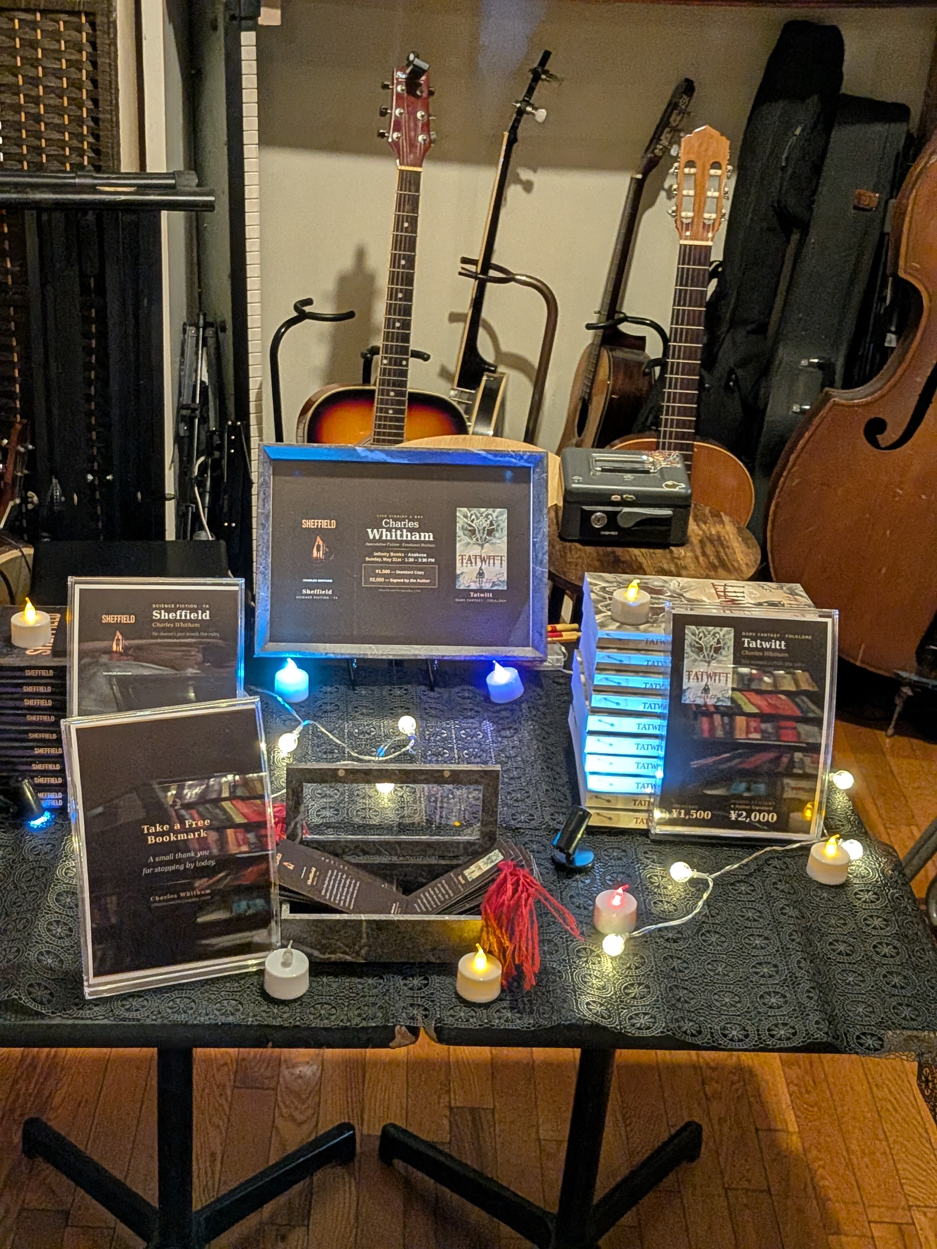 Author table setup at Infinity Books with both books, candles, and fairy lights